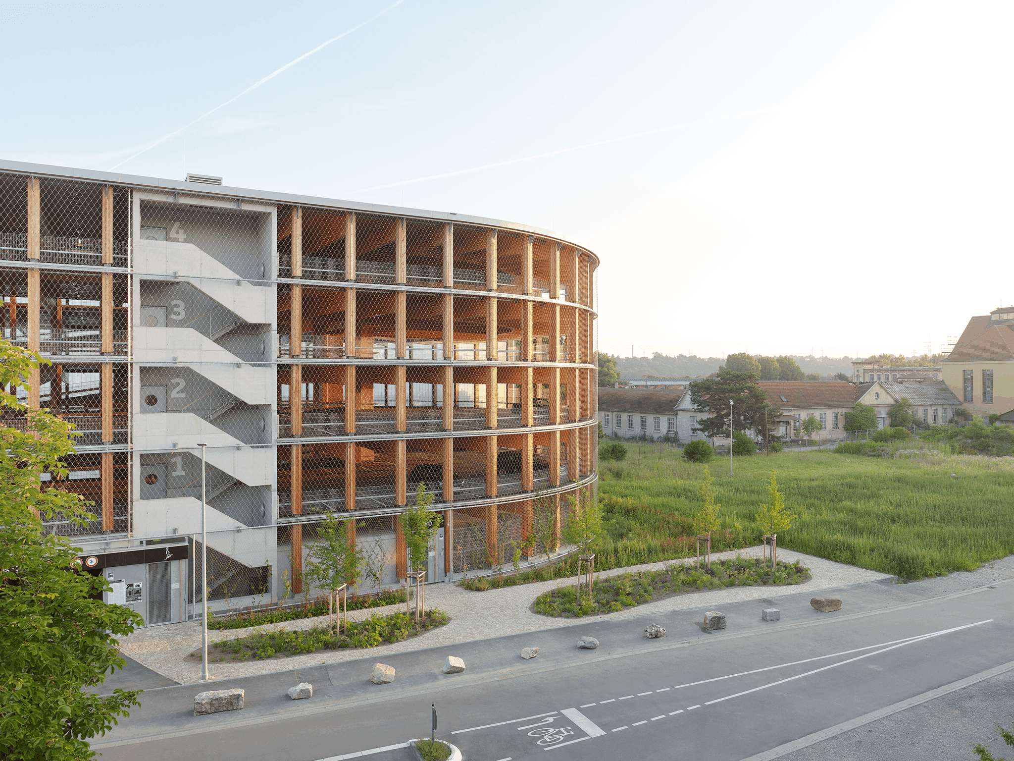 Ovales, fünfgeschossiges Parkhaus aus Holz in Wendlingen am Neckar, klimaneutral gebaut, mit natürlicher Belichtung und Fassadenbegrünung; dient als zukunftsfähige Mobilitätsdrehscheibe und ist vollständig rückbaubar.
