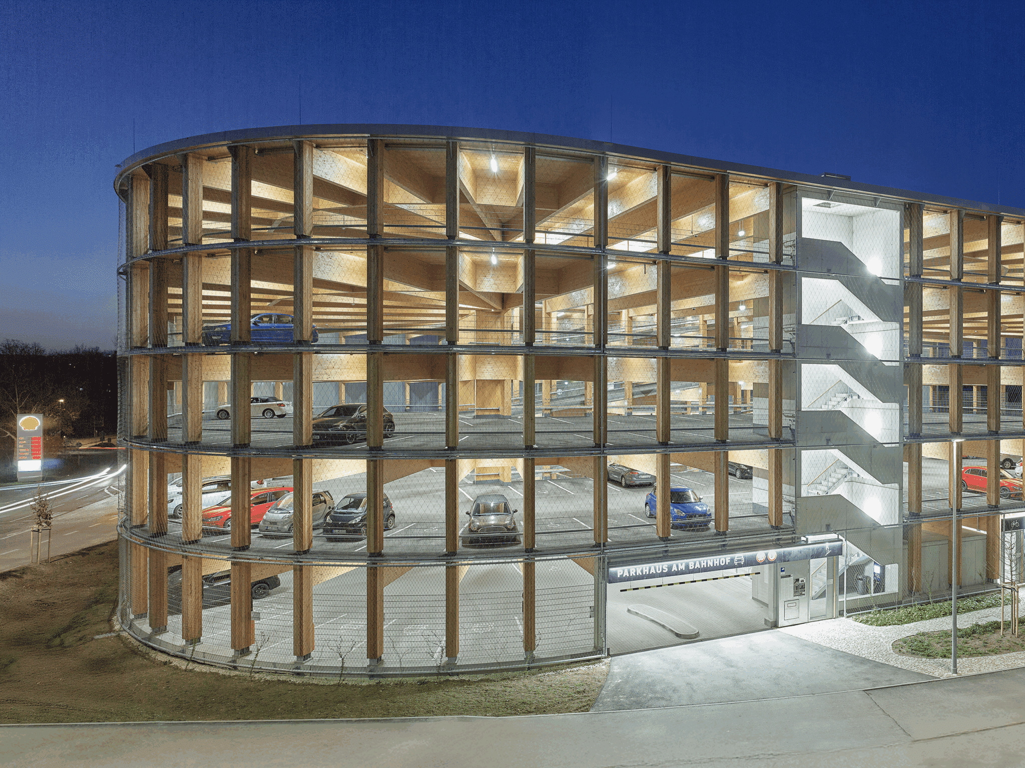 Ovales, fünfgeschossiges Parkhaus aus Holz in Wendlingen am Neckar, klimaneutral gebaut, mit natürlicher Belichtung und Fassadenbegrünung; dient als zukunftsfähige Mobilitätsdrehscheibe und ist vollständig rückbaubar.