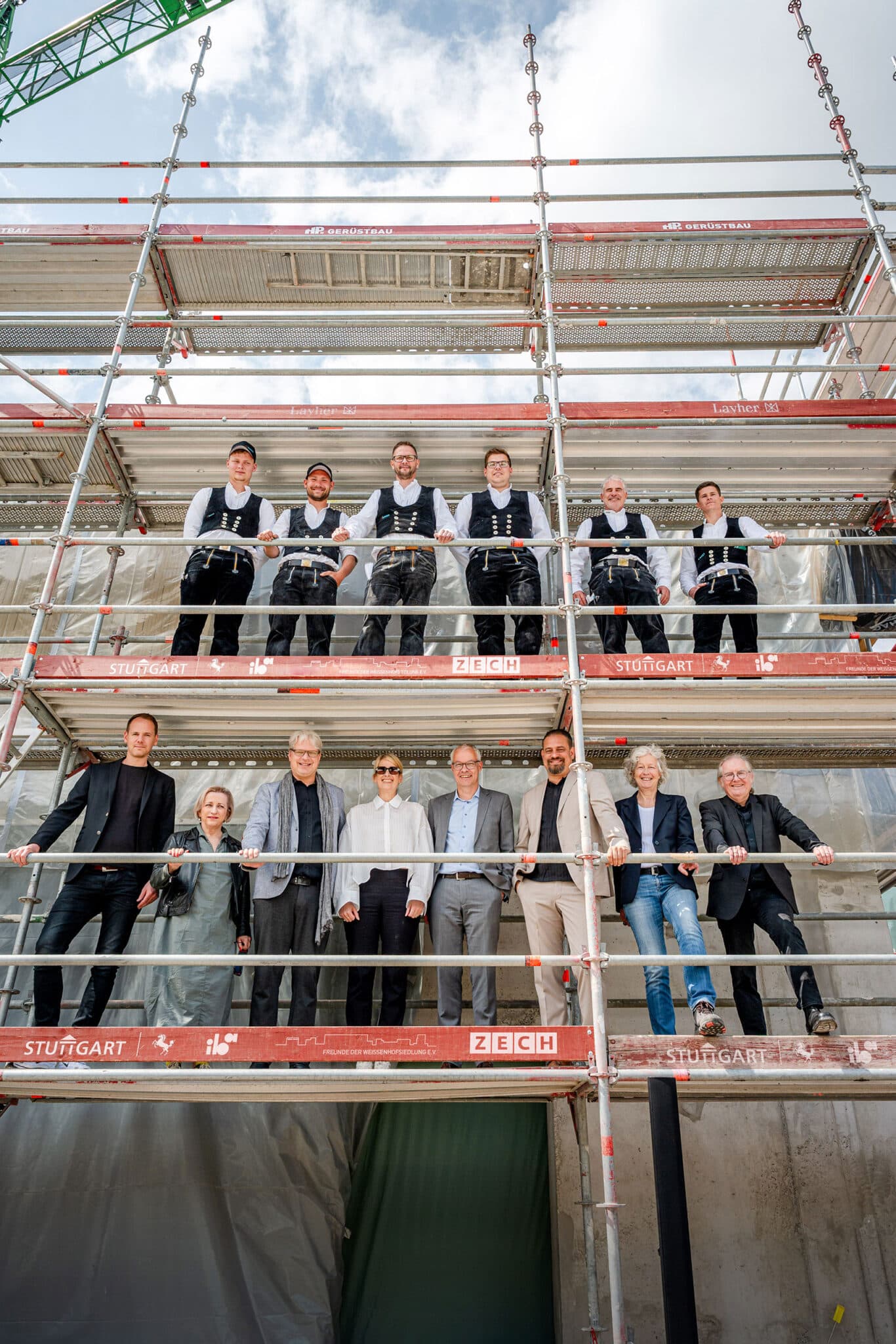 Zimmerleute und Projektbeteiligte auf dem Baugerüst vor dem Weissenhof-Forum während des Richtfests.