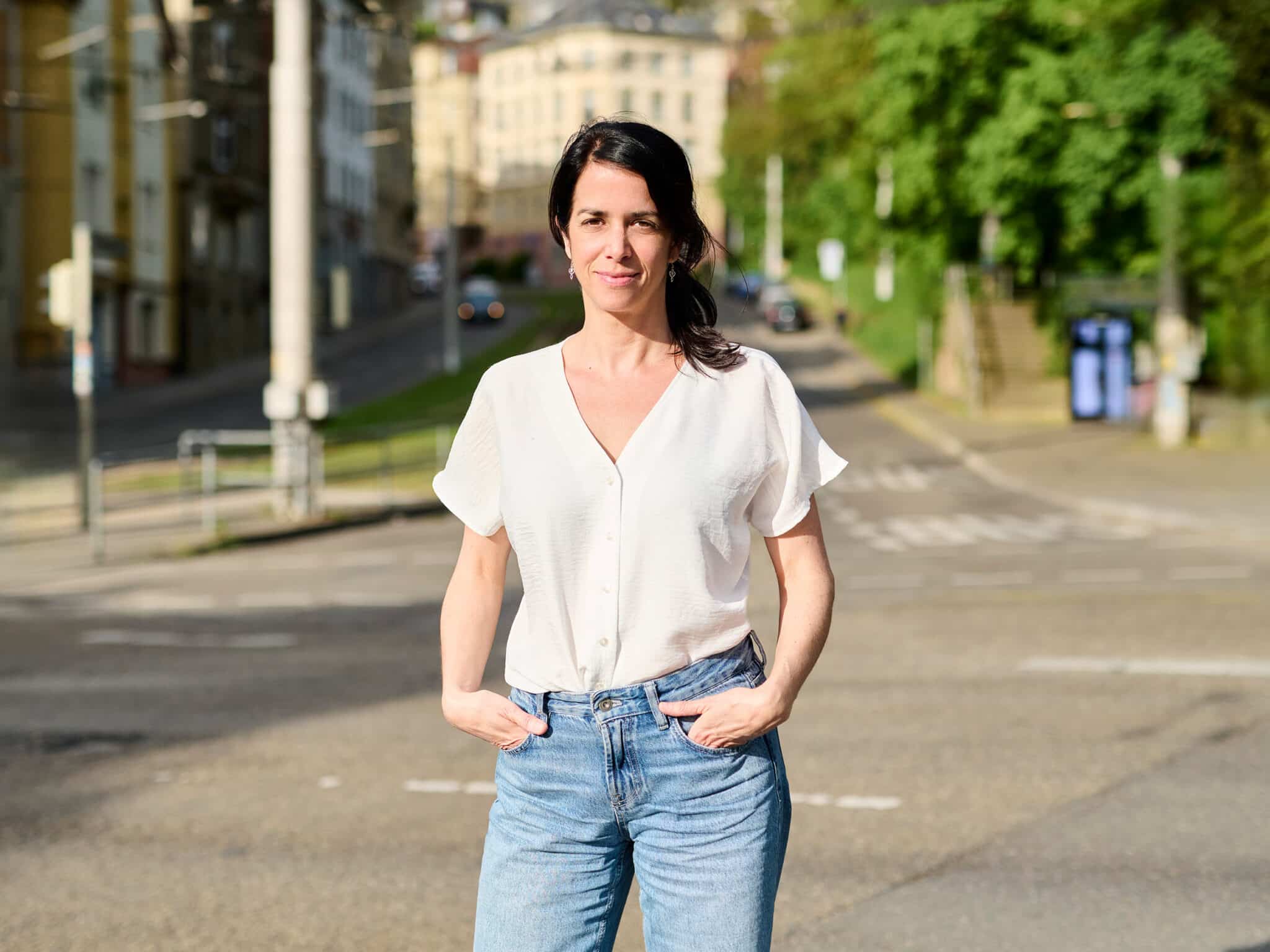 Roberta de Seriis steht im öffentlichen Stadtraum, im Hintergrund verdichtete urbane Bebauung mit Straßenraum und Fassaden.